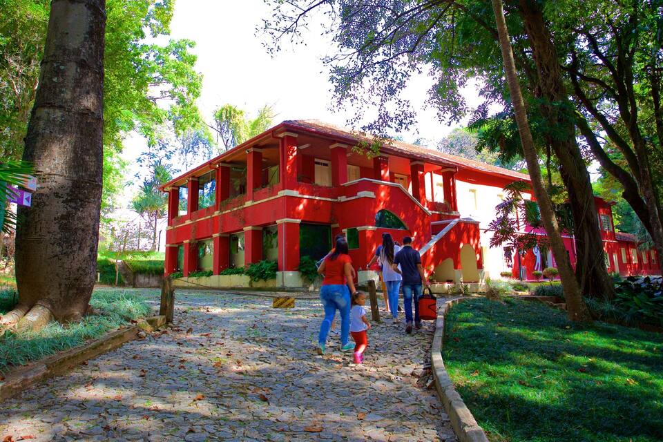 A red building surrounded by trees and a cobblestone path.