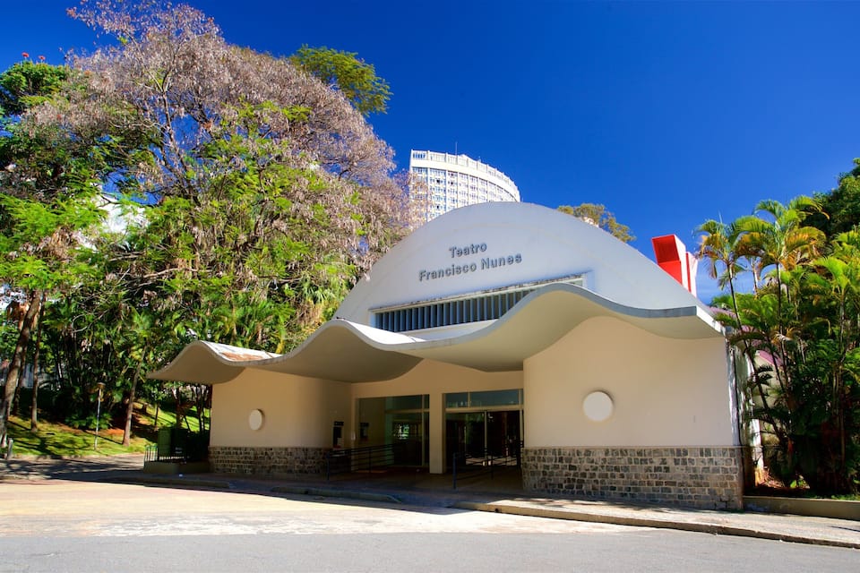 Teatro Francisco Nunes com fachada curva singular, rodeado por vegetação exuberante e palmeiras.