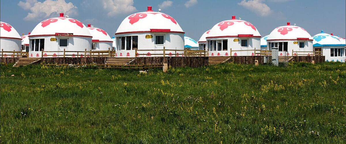Yurts with red and white domes in a grassy field.