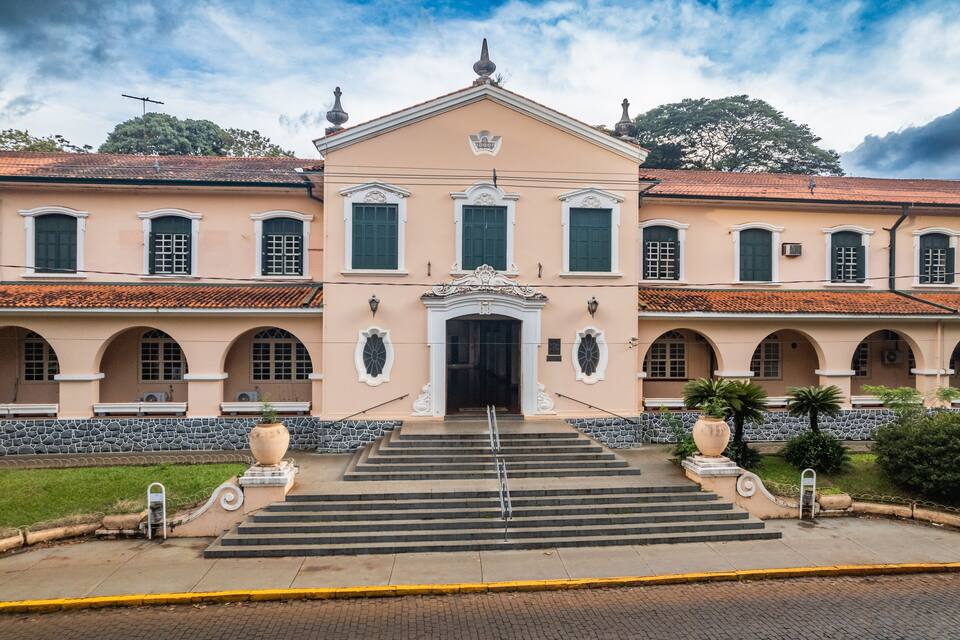 A large, historic building with a symmetrical facade, arched windows, and a central entrance.