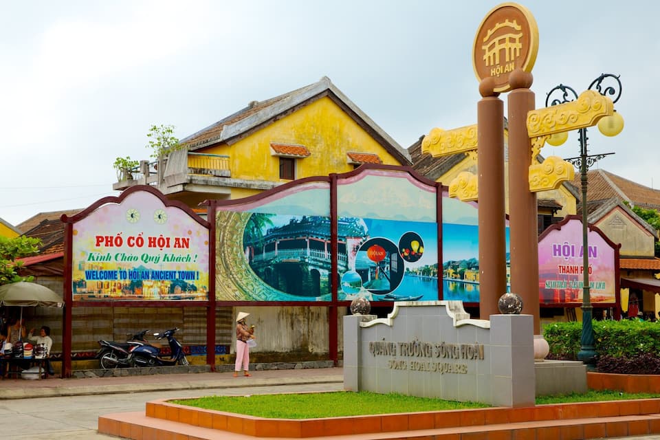 A colorful entrance sign for Hoi An Ancient Town, featuring traditional architecture and a welcoming message.