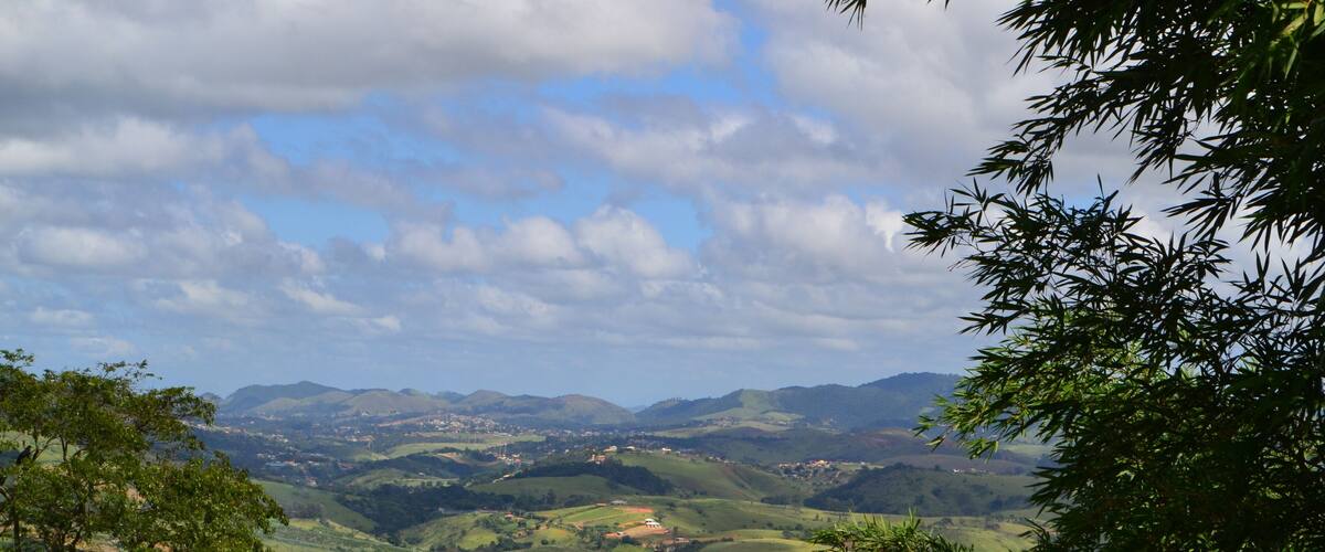 A valley with rolling hills, scattered houses, and a prominent tower.