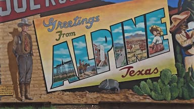 A mural with a cowboy, a woman in a dress, a coyote, and a cactus.