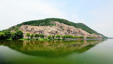 Um lago sereno com uma ilha rochosa, apresentando ruínas antigas e vegetação exuberante.