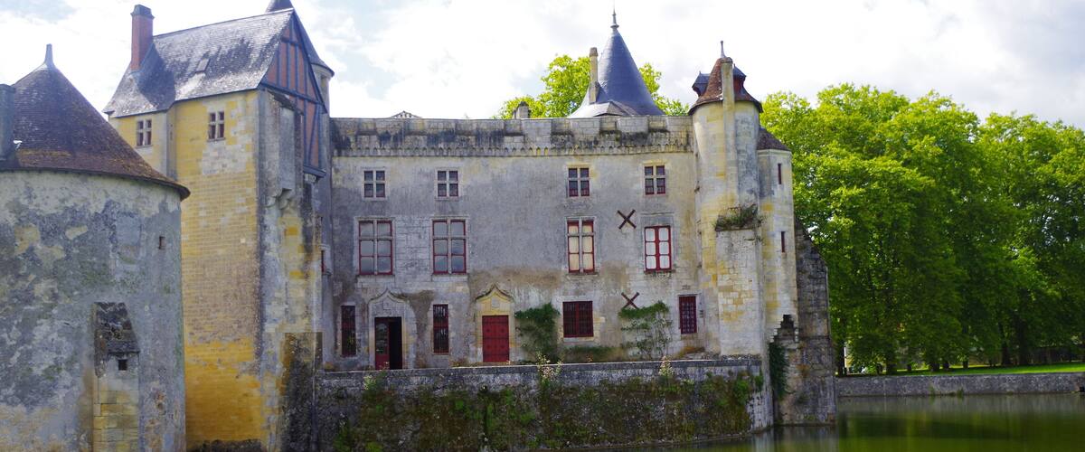 A historic castle with a moat, red doors, and a tower.
