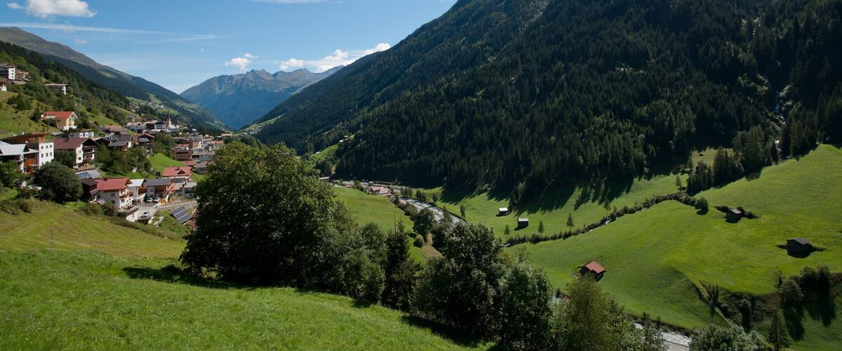 A valley with a small town nestled among green hills and mountains.