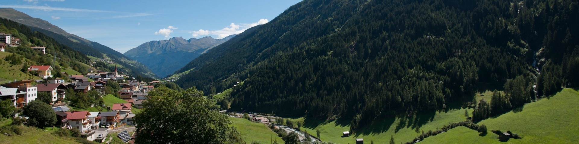 A valley with a small town nestled among green hills and mountains.