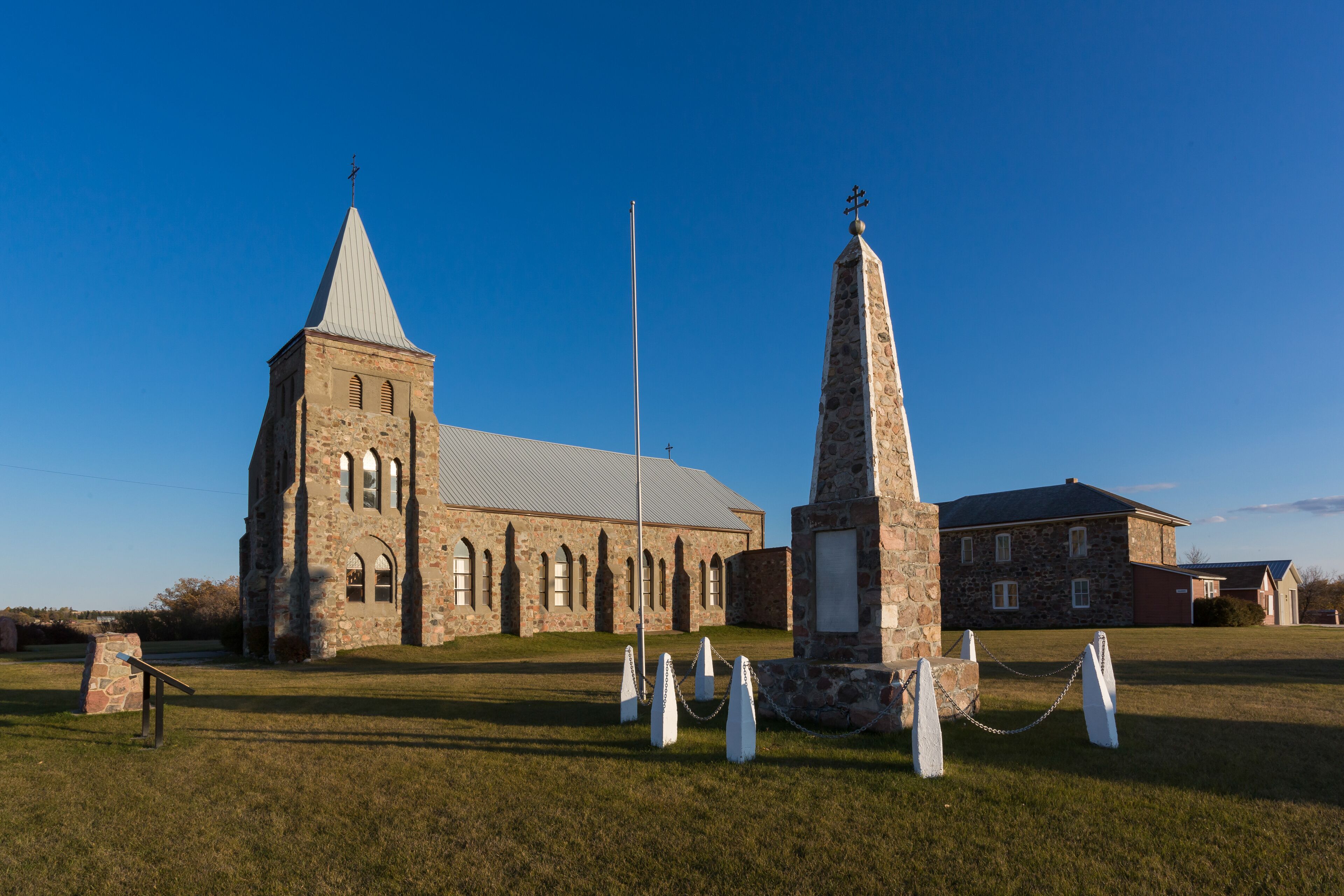A historic stone church with a bell tower and a tall monument.