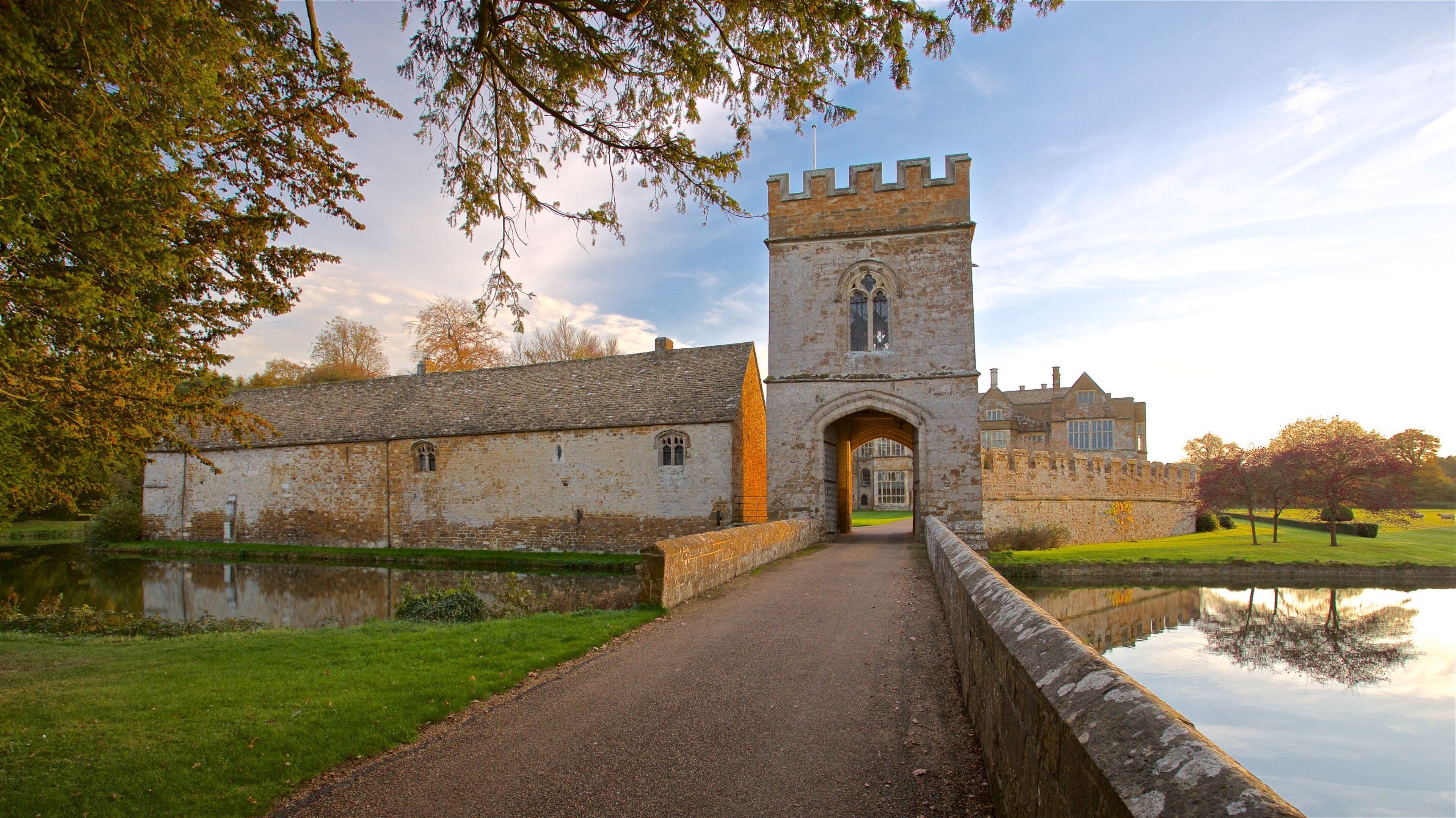 Broughton Castle which includes a lake or waterhole, a sunset and chateau or palace