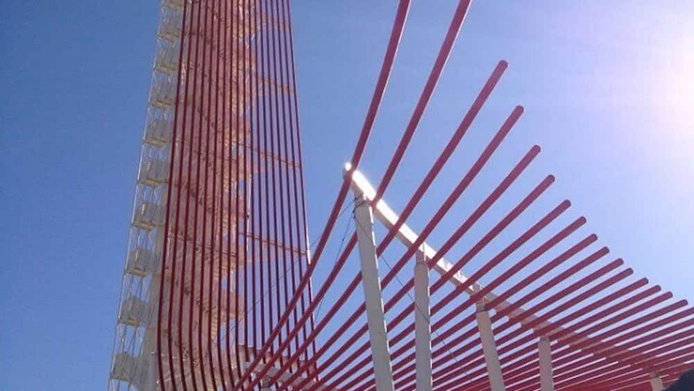 A tall building with a red metal framework and a clear blue sky.