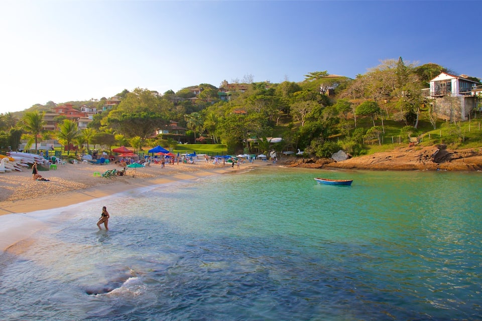 A beach with clear turquoise water, a row of boats, and a few people.