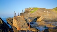 A coastal stone structure with rusted metal poles and a small bridge.