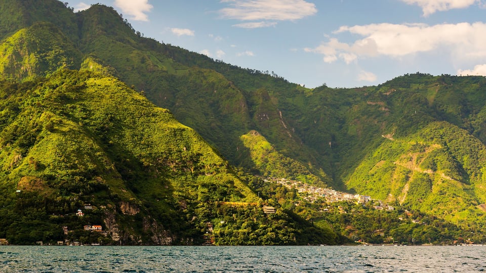 A coastal village nestled in green hills with a clear view of the sea.