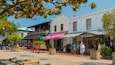 Une rue animée où l’on peut admirer une calèche d’époque, un marché municipal et diverses boutiques.