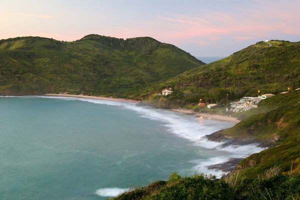 Un paysage côtier avec une plage, des collines et des bâtiments.