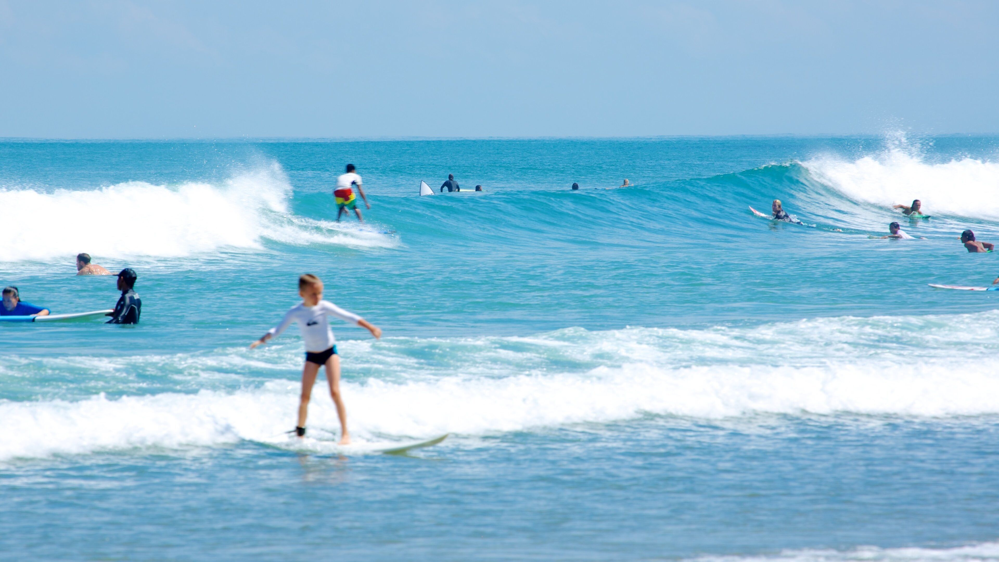 A group of surfers in the ocean with waves suitable for surfing.