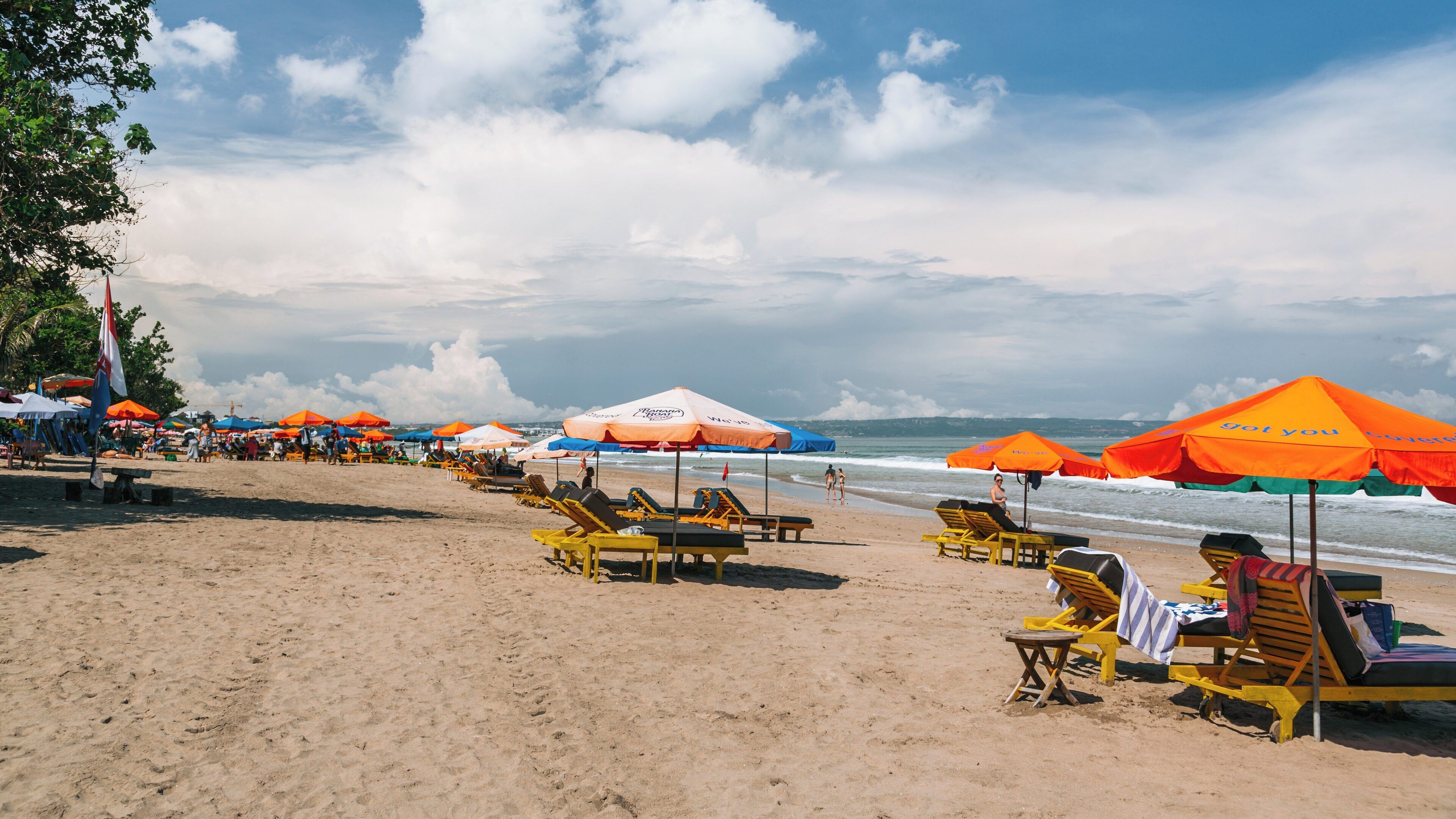 Relaxation and leisure at Double Six Beach in North Legian, Kuta, Bali under a bright sky with vibrant beach umbrellas and sun loungers