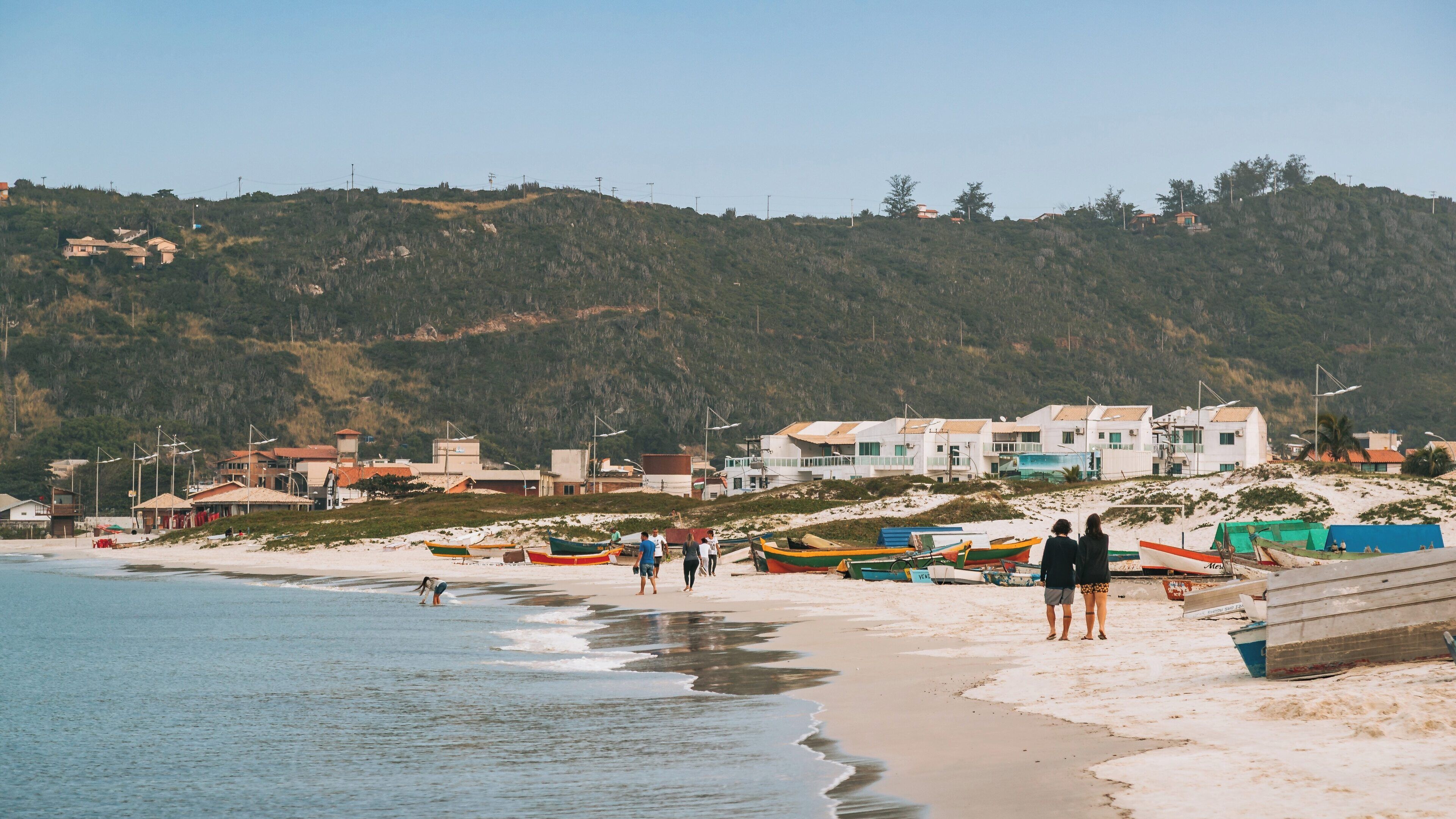 Exploring the sandy shores of Forno Port in Buzios, Rio de Janeiro with colorful boats and beachgoers enjoying the day