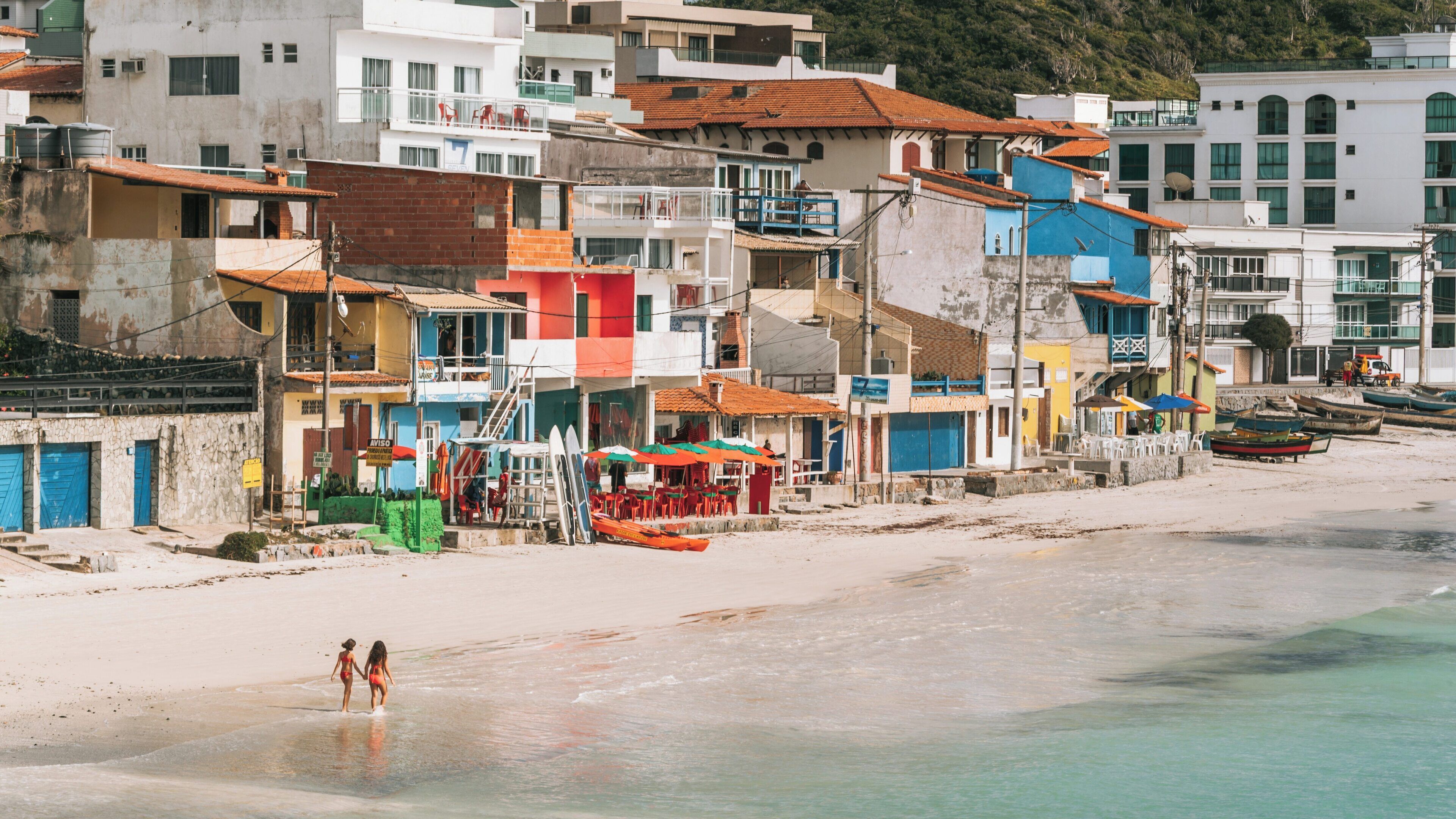 Prainha Beach in Arraial do Cabo showcases colorful buildings, sandy shores, and visitors enjoying the sun in Rio de Janeiro, Brazil