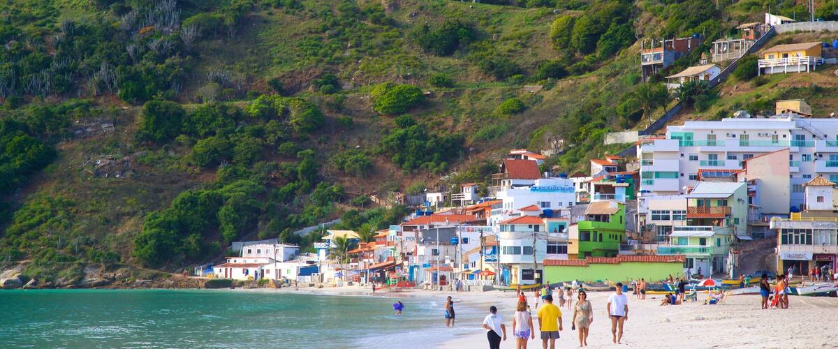 Une ville côtière aux bâtiments aux couleurs vives, dotée d’une plage de sable et d’une colline verdoyante.
