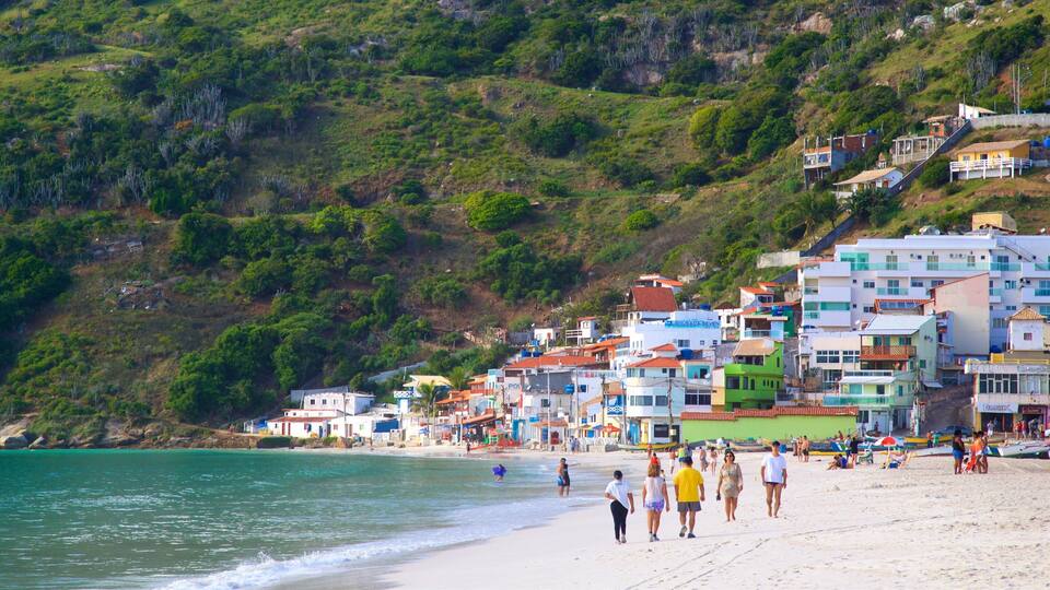 Un poble costaner amb edificis de colors, una platja sorrenca i un turó amb vegetació.