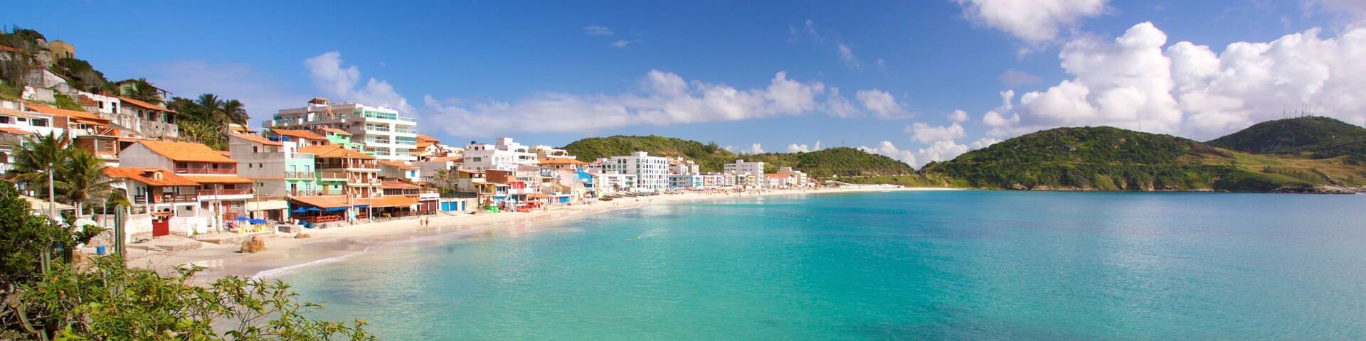 A coastal town with clear turquoise waters, a sandy beach, and buildings along the shore.