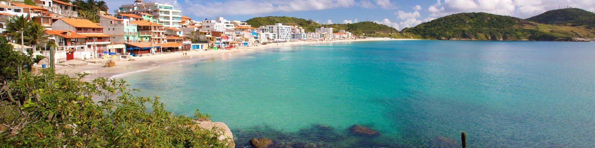 Un pueblo costero con aguas turquesas cristalinas, una playa arenosa y edificios a lo largo de la costa.