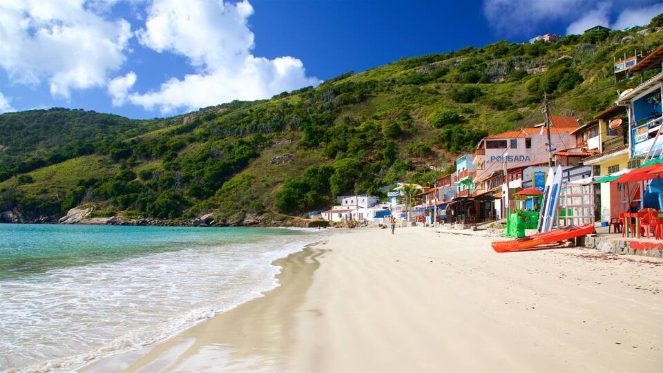 A beach with turquoise water, a sandy shore, and buildings with colorful facades.