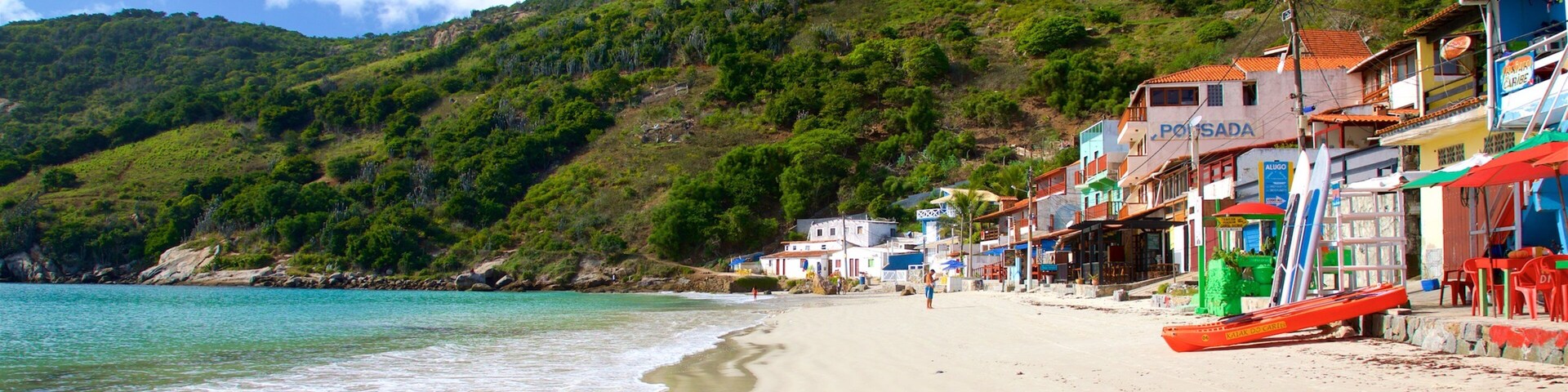 Una playa con aguas turquesas, una orilla arenosa y edificios con fachadas coloridas.