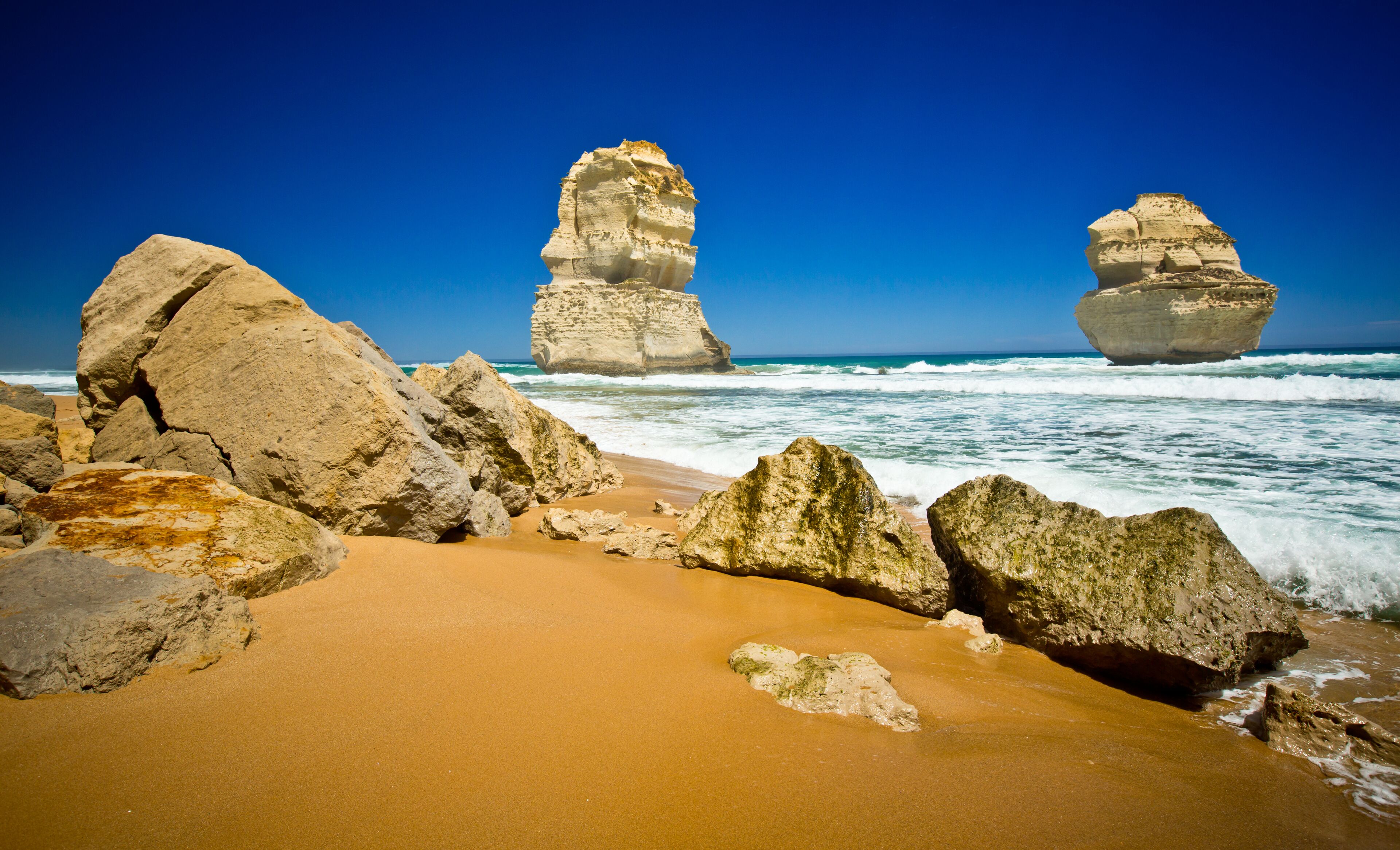 A coastal landscape with large rock formations and a sandy beach.