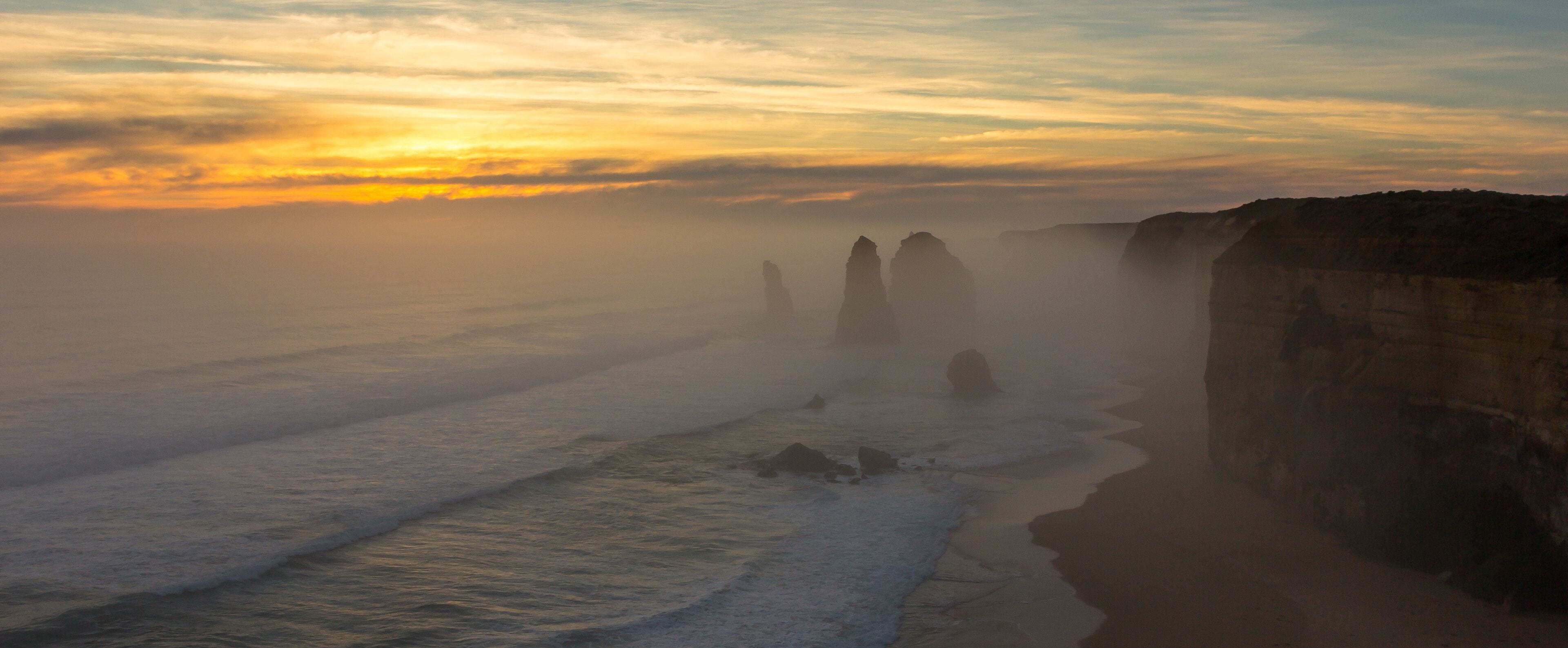Un paisaje costero con un acantilado y olas al atardecer.