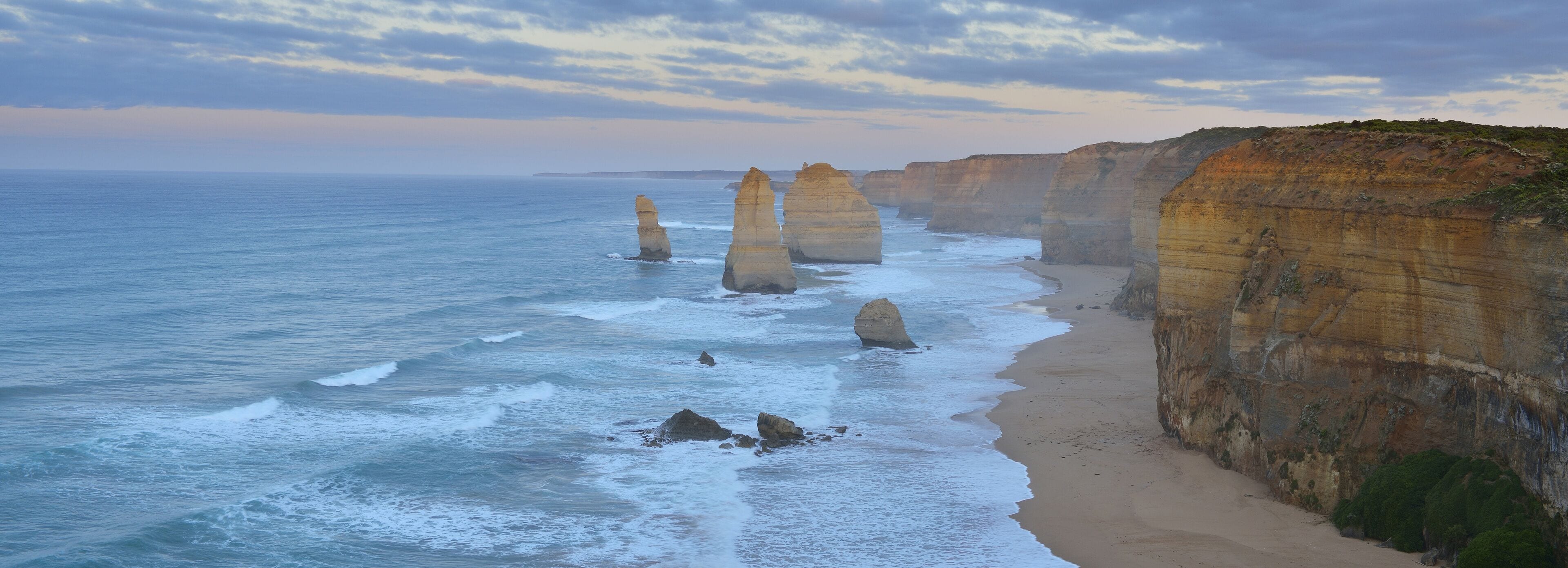 A coastal landscape with prominent rock formations along the shoreline.