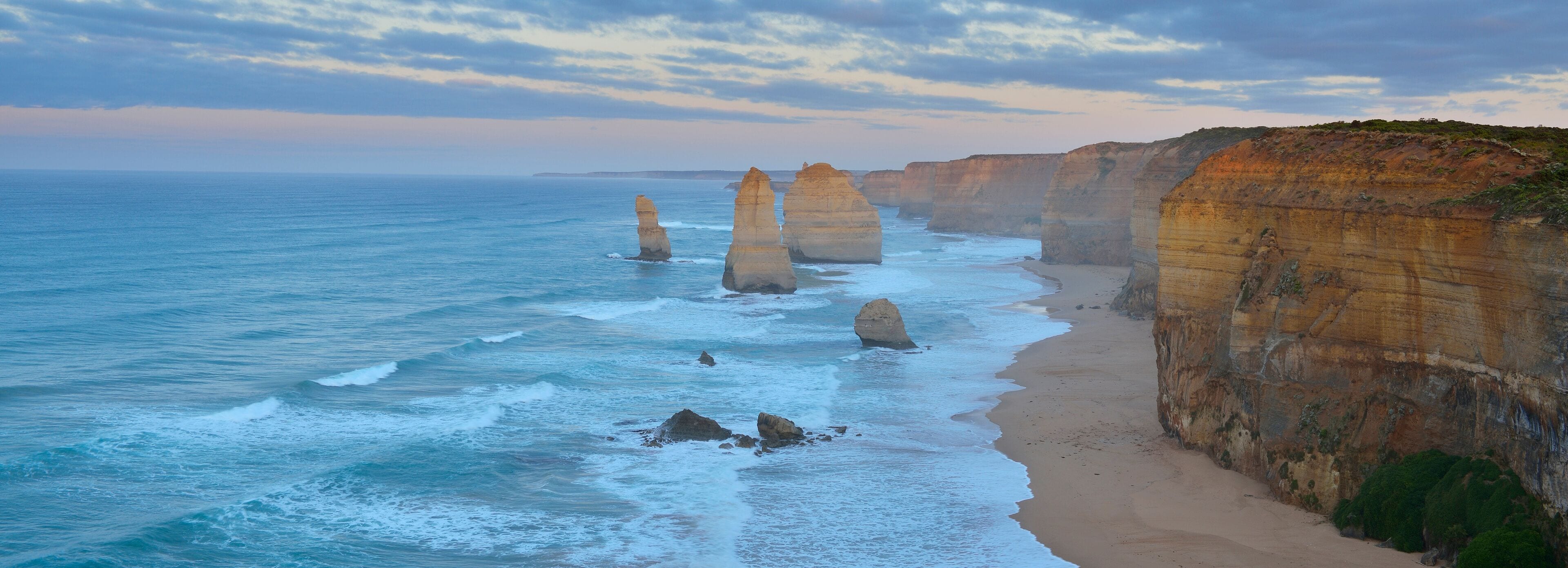 A coastal landscape with towering rock formations and a sandy beach.