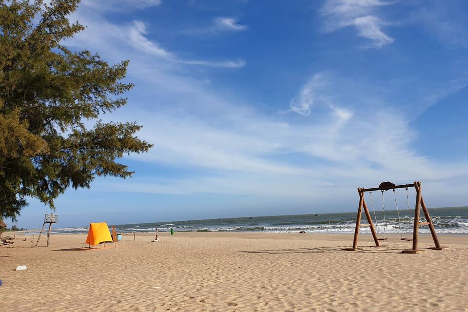 A beach with a swing set, a lifeguard tower, and a flag.