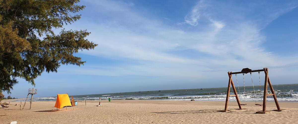 A beach with a swing set, a lifeguard tower, and a flag.