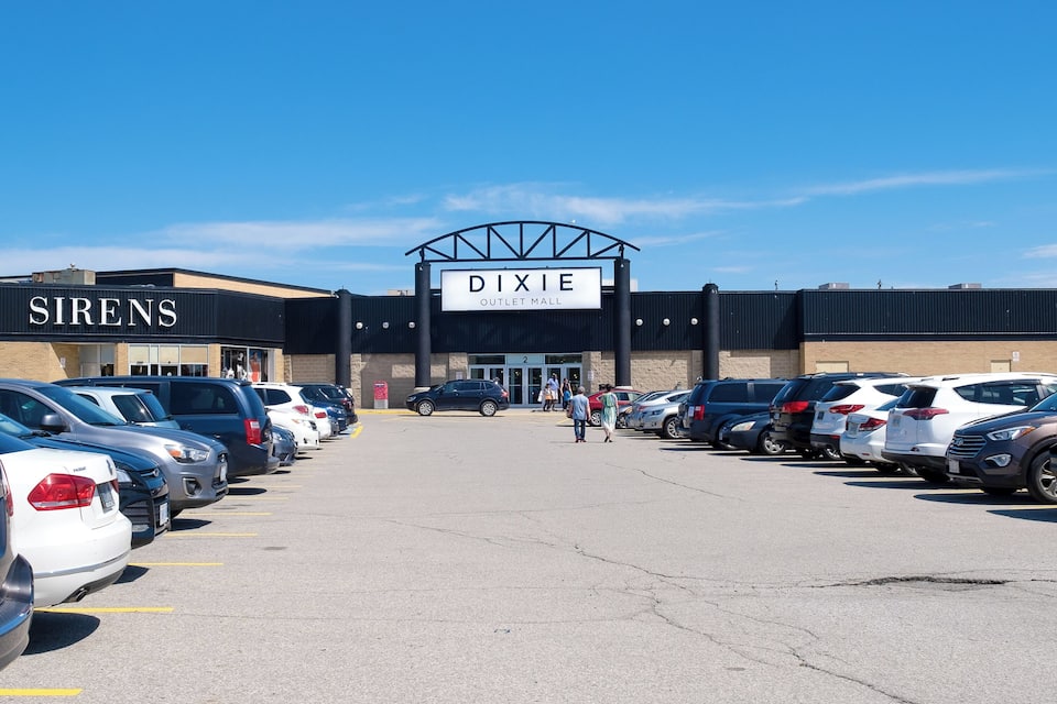 Un estacionamiento frente al centro comercial Dixie Outlet Mall con una tienda Sirens.
