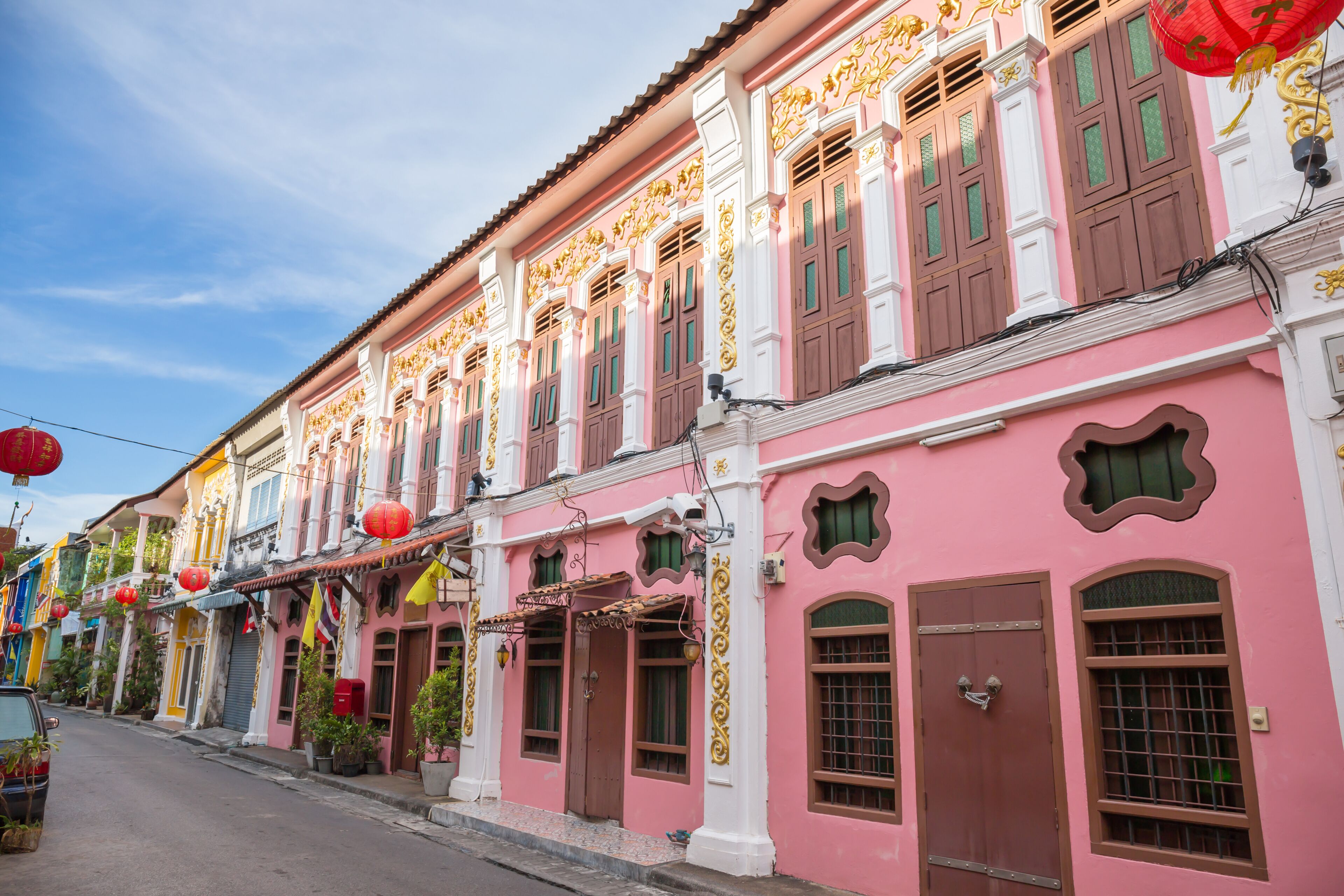 Uma fileira de edifícios tradicionais coloridos, com decorações elaboradas e lanternas vermelhas.
