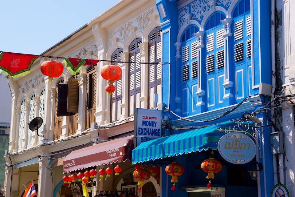 A traditional building with ornate architecture, a sign for an old town money exchange, and red lanterns hanging outside.