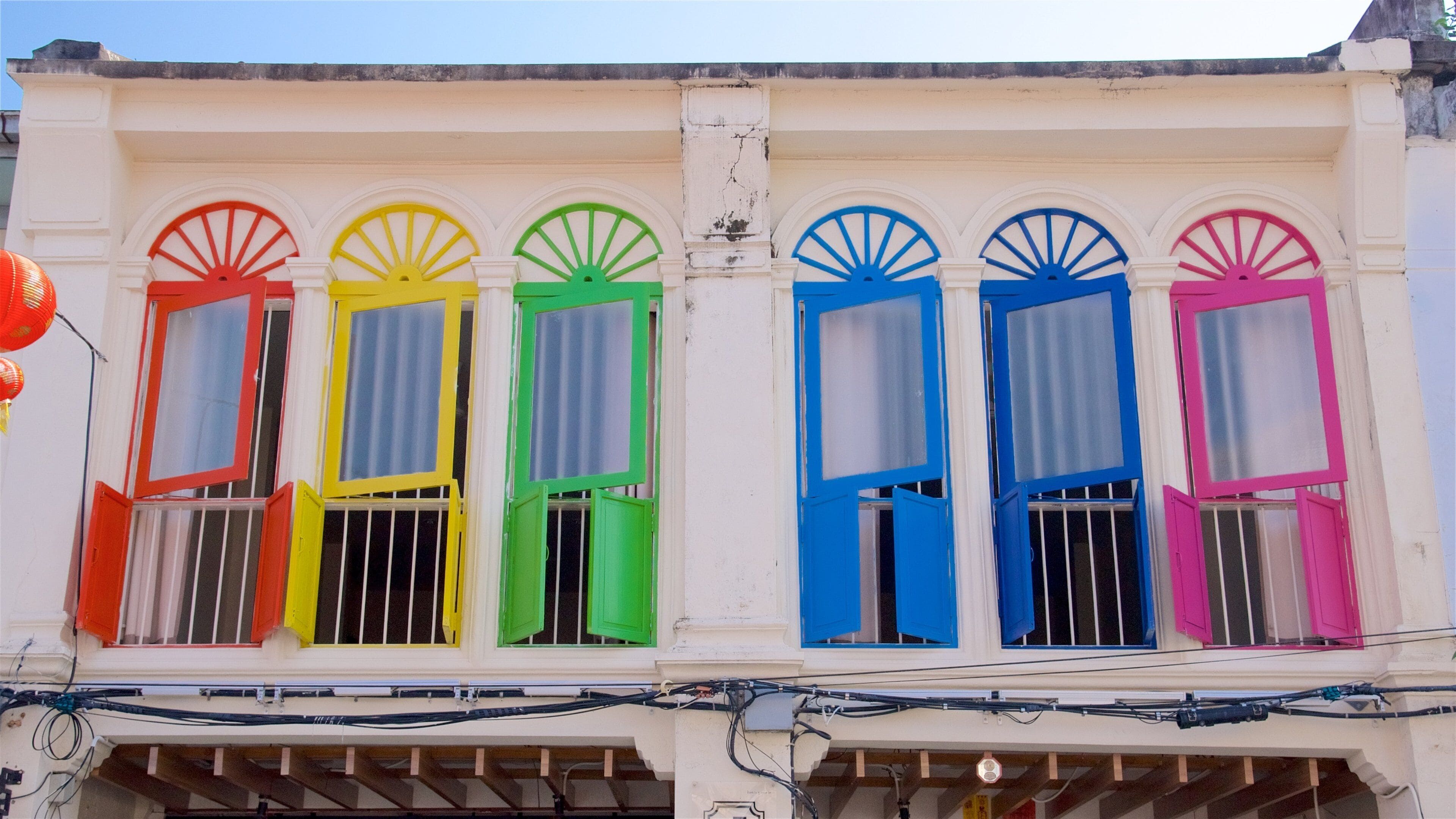 Una hilera de ventanas coloridas con contraventanas en la fachada de un edificio.
