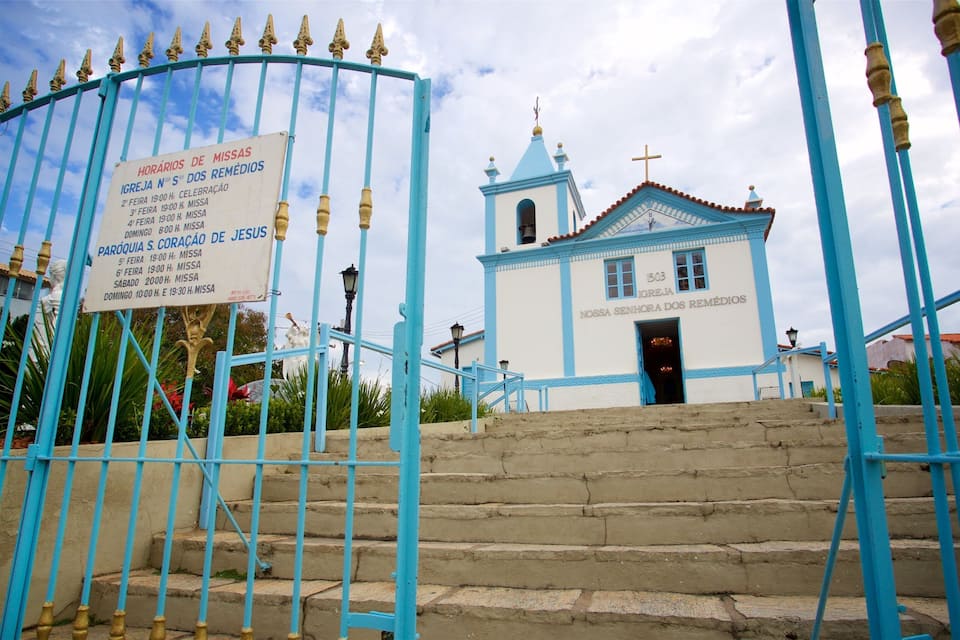 Une église à la façade bleue et blanche, surmontée d’une croix, et sur laquelle est affiché un panneau indiquant les horaires des événements.