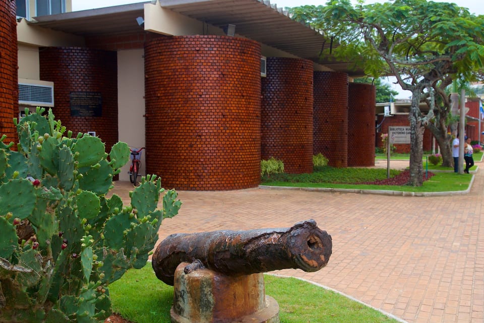 A cactus, a rusted cannon, and a brick building with columns.