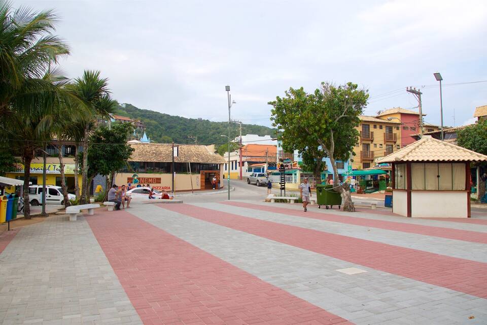 A paved square with red and grey tiles, palm trees, and buildings with colorful facades.