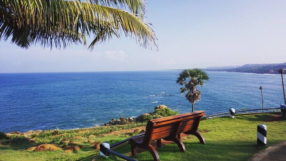 Un banc en bois offrant une vue sur la côte, avec l’océan et une ligne de rivage lointaine.