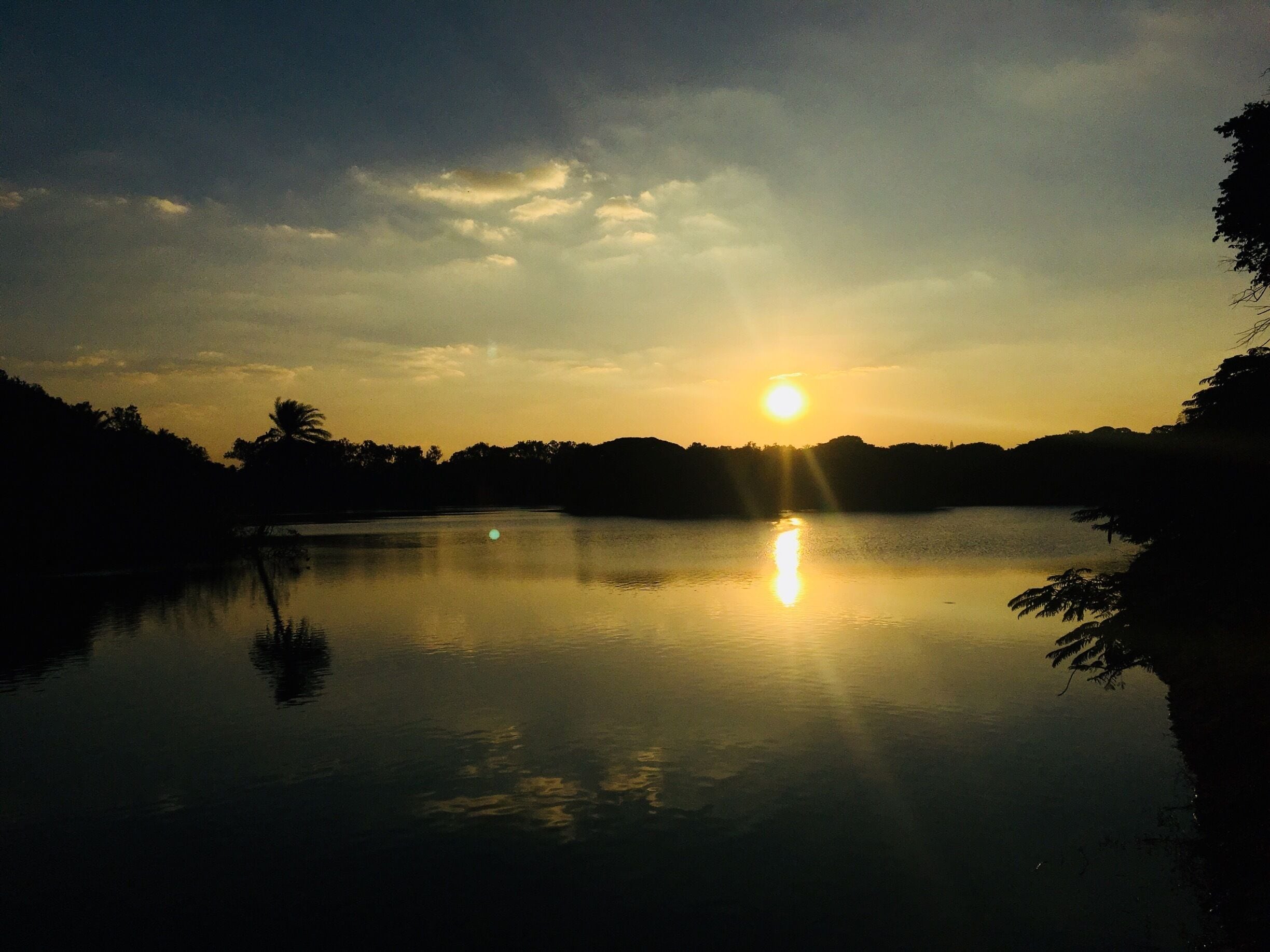 Un atardecer sobre un lago tranquilo, con reflejos del sol en el agua.