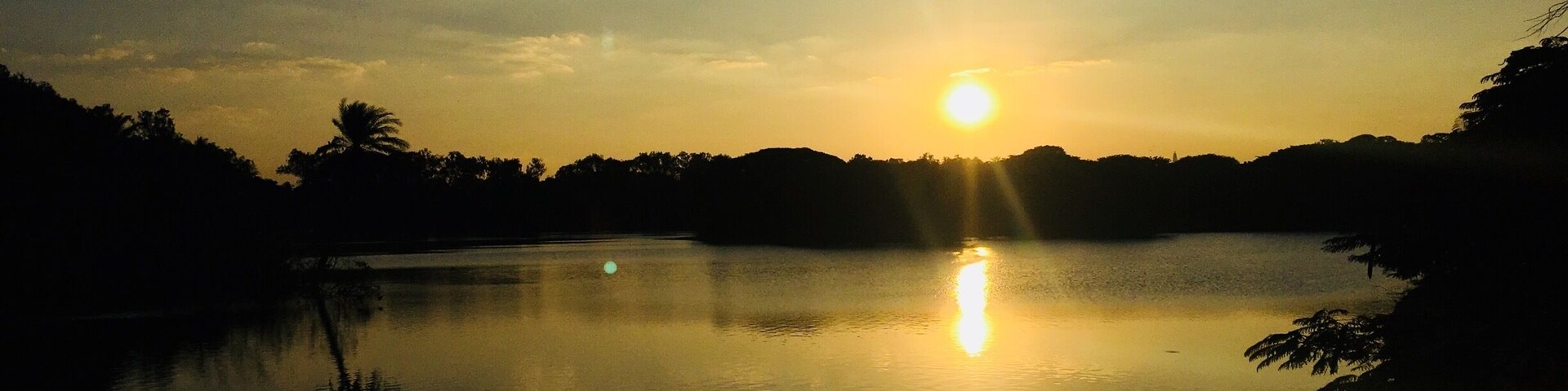 Un atardecer sobre un lago tranquilo, con reflejos del sol en el agua.