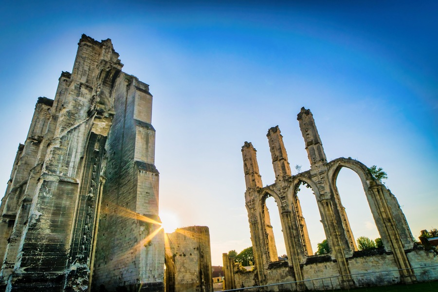 Dramatic Saint Bertin abbey ruins in Saint-omer in France during the sunrise with sun flare on the backgroudn.No poeple. Empty spce background.