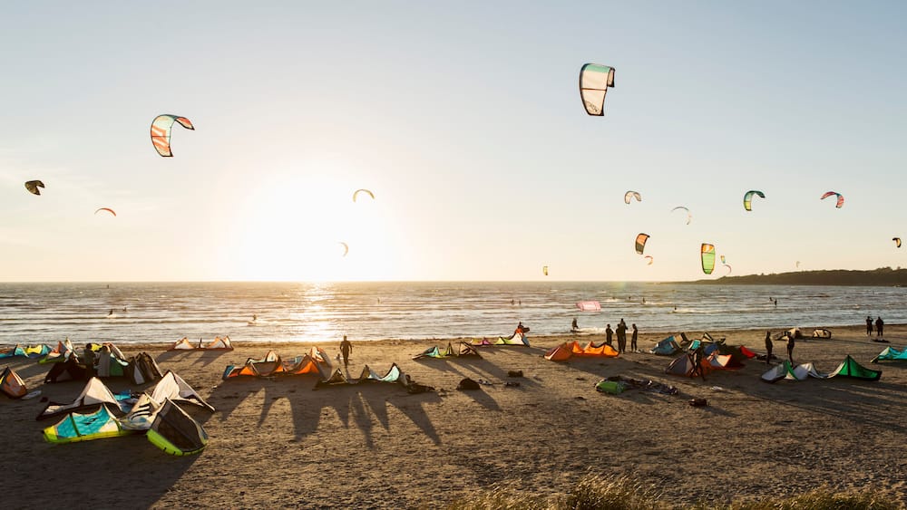 Kiteboarders on beach against clear sky