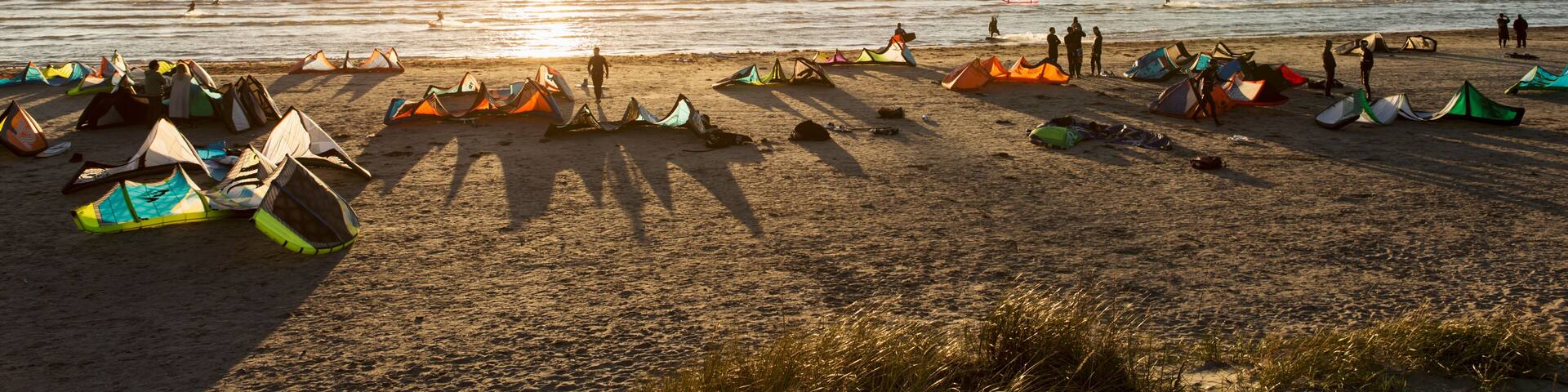 Kiteboarders on beach against clear sky