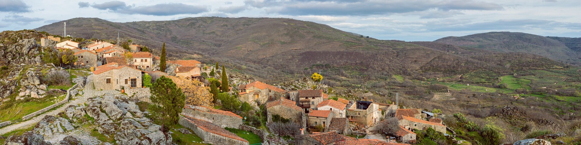 Uma aldeia montanhosa com edifícios de pedra e campos em socalcos.