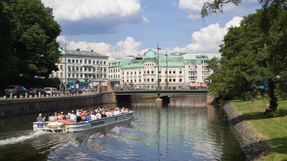 A boat on a river with a bridge and buildings in the background.